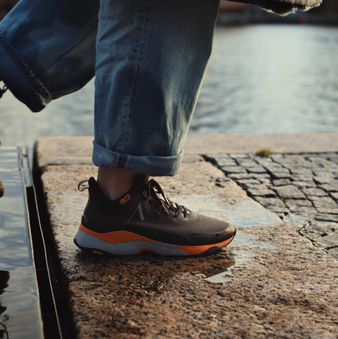 A person walking in water puddles with brown Arket sneakers