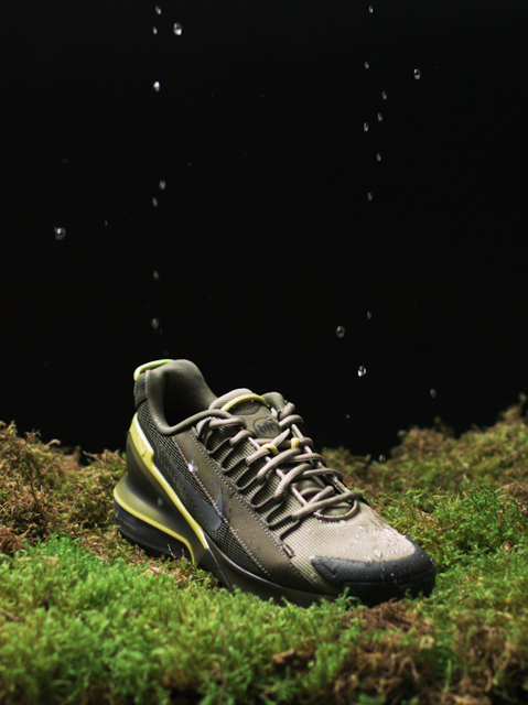 IMBOXed green and brown Nike outdoor shoe standing on moss and repelling waterdrops