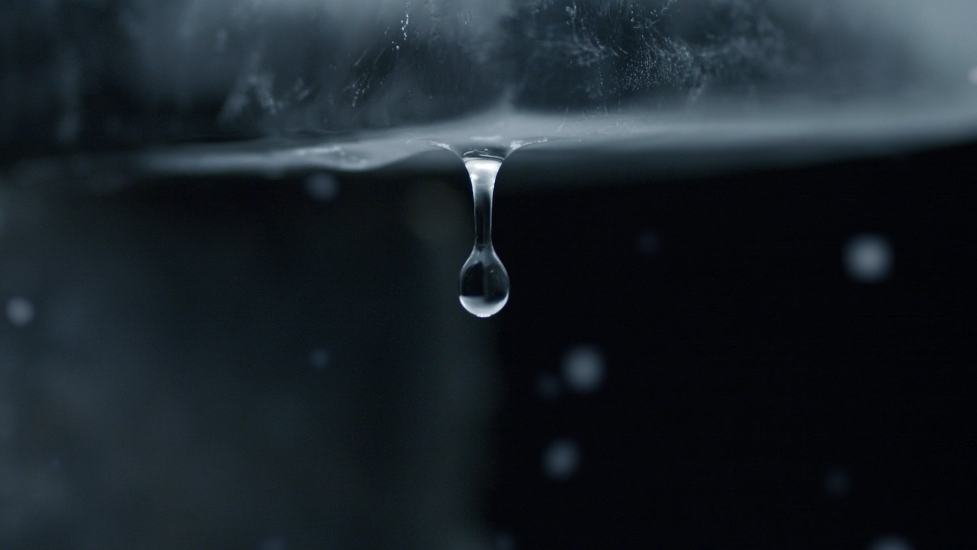 Dripping water drop falling from the icecube