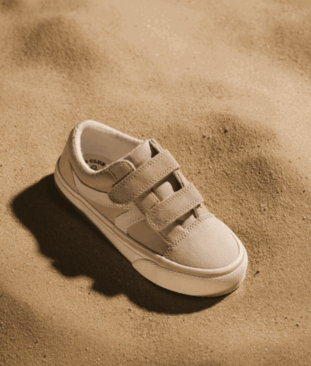 IMBOXed beige children canva shoe placed on top of sand