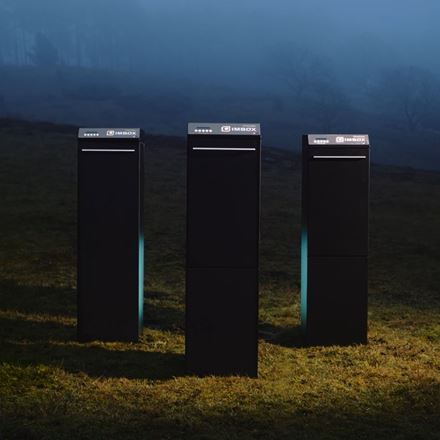 Three black IMBOX Originals seen in front view standing in the night with spotlight on