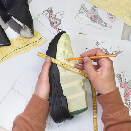 A person measures and draws on sneaker