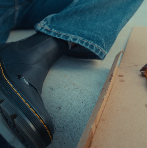 Black Dr. Martens boots next to a pizza slice