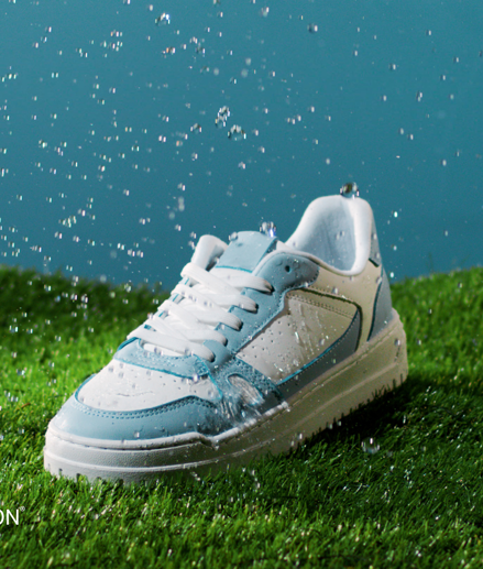 Blue and white Addidas sneaker standing on grass lane repelling raindrops