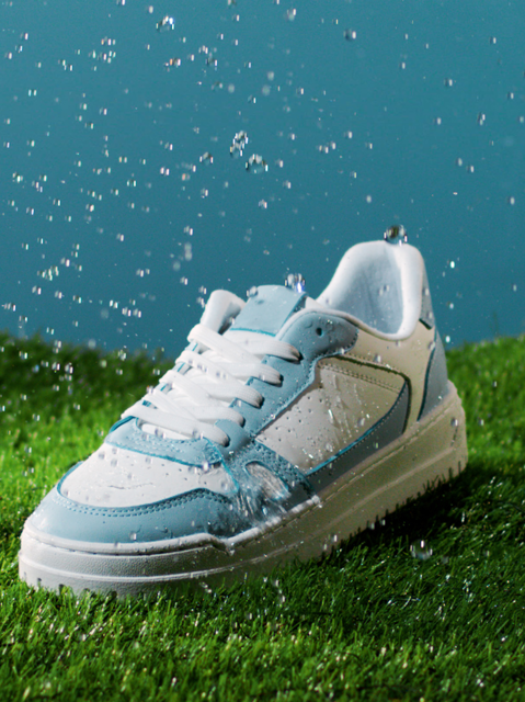 Blue and white Addidas sneaker standing on grass lane repelling raindrops