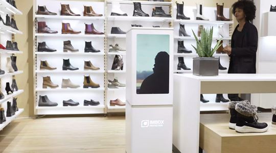 White IMBOX Flagship standing in shoe store with video on the screen next to the cashier