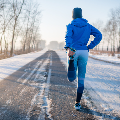 Runner in blue workout clothes standing in the street in the winter