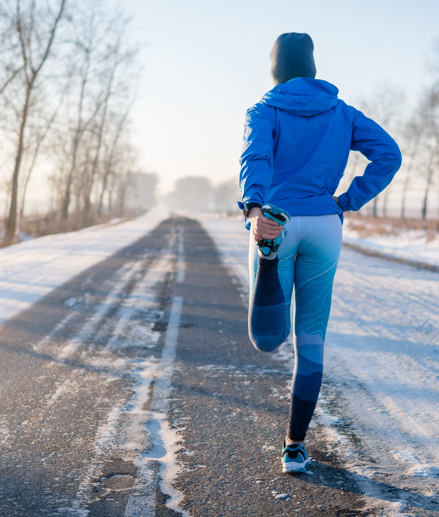 Runner in blue workout clothes standing in the street in the winter