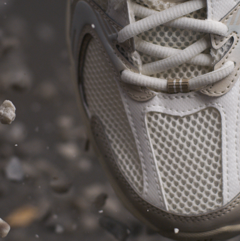 Close-up of white and beige sneaker surrounded by stones