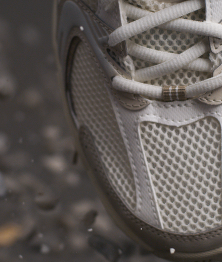 Close-up of white and beige sneakers surrounded by stones