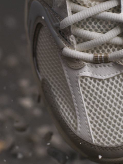 Close-up of white and beige sneaker surrounded by stones