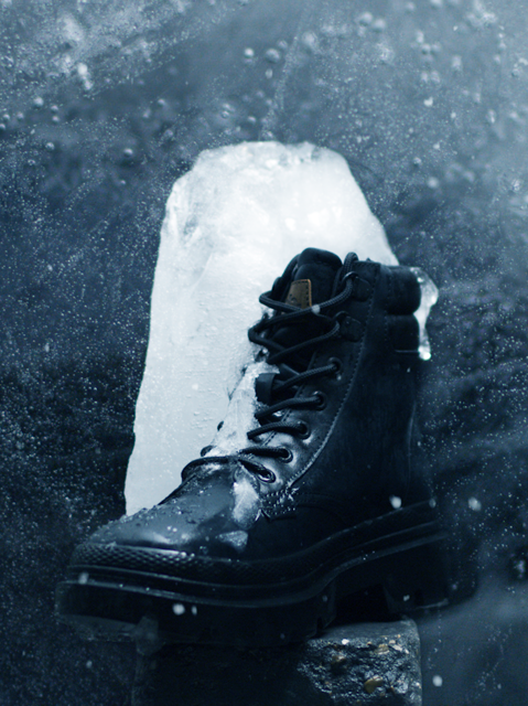 A chunk ofice frozen to a black winter boot 