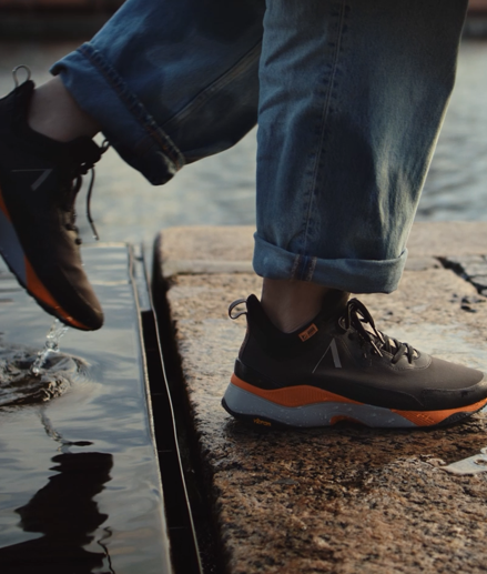 A person walking in water puddles with brown Arket sneakers