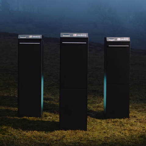 Three black IMBOX Originals standing next to each other outside on the grass with spotlight on