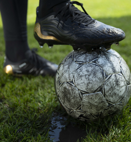 Black football shoes on top of a football