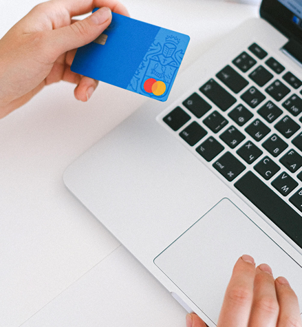 Woman shopping online on MacBook paying with her Mastercard