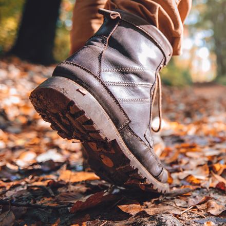 Person in brown boots walking in the forest at fall