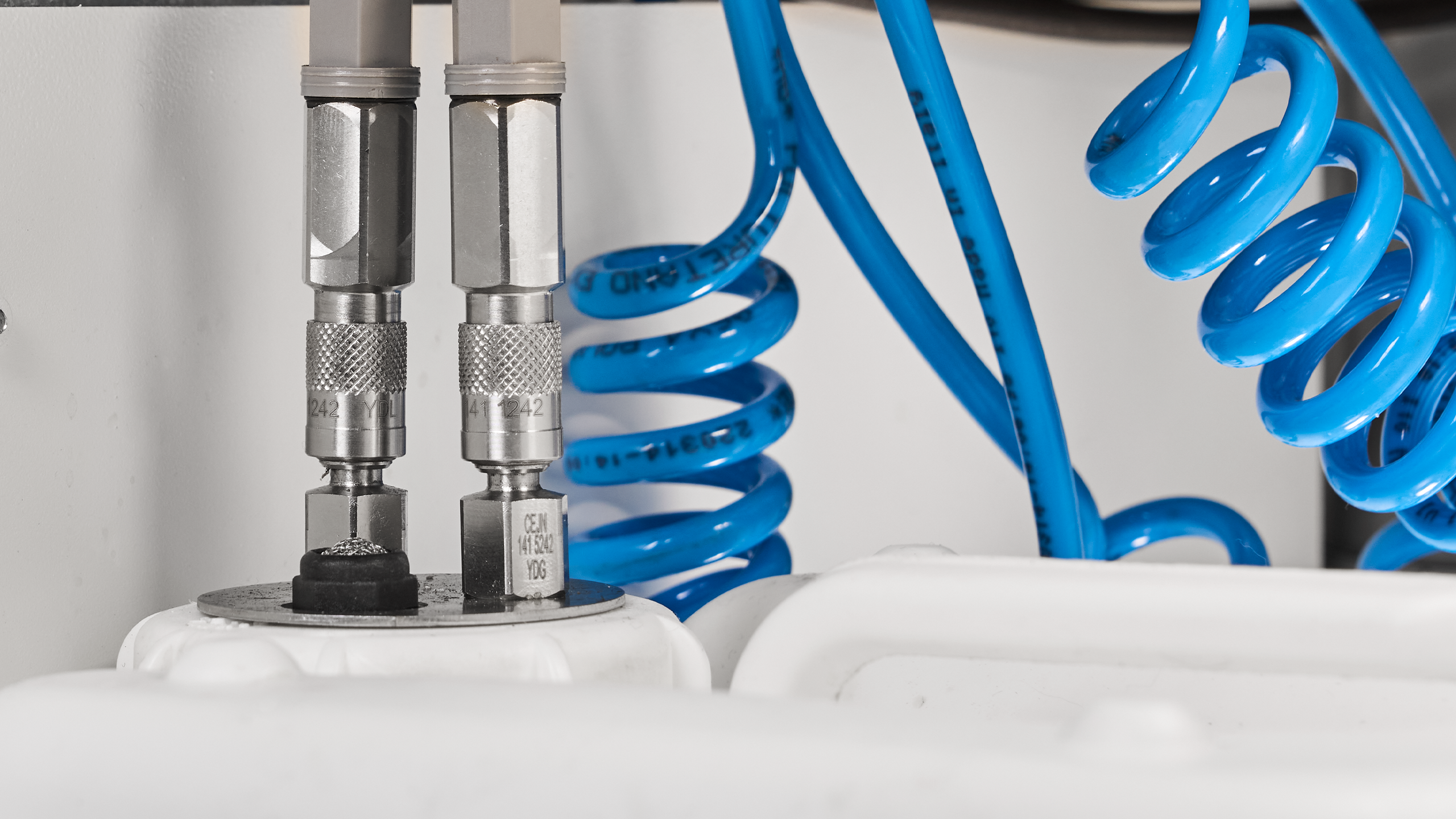 Close-up of mechanical components and tubing attached to a black plastic cap