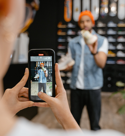 Employee recording video of a man who showcase sneakers in a shoe store