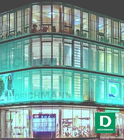 View of Deichmann store in four levels in the evening with green and white Deichmann logo